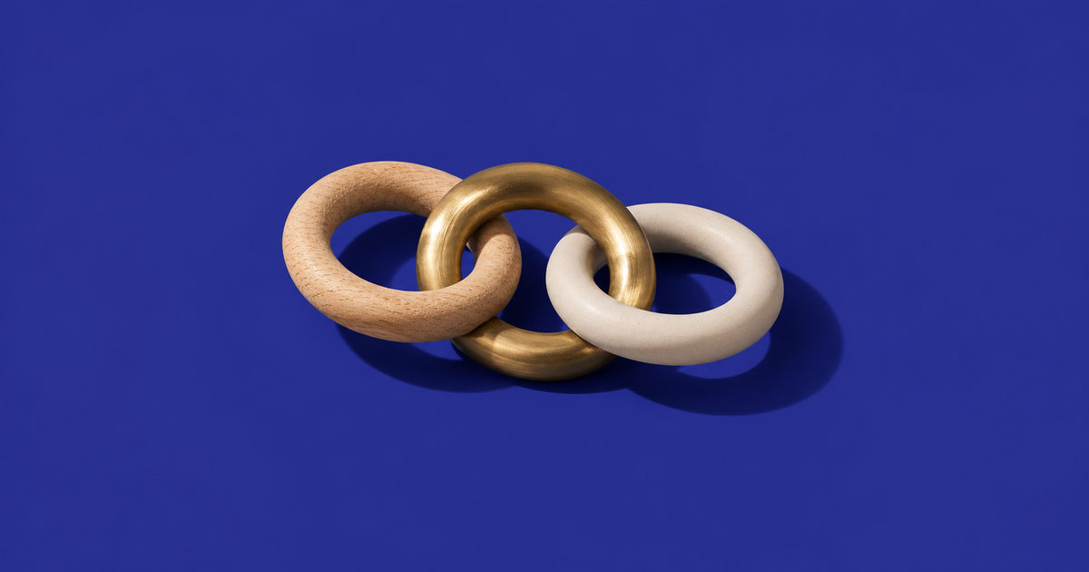 Tres aros de madera, latón y cerámica mate enlazados entre sí sobre fondo azul oscuro