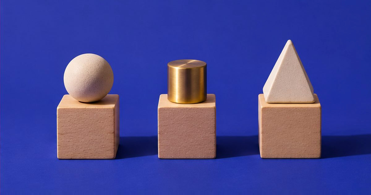 Tres bloques de madera iguales, cada uno con una pieza distinta encima: una esfera, un cilindro de latón y una pirámide