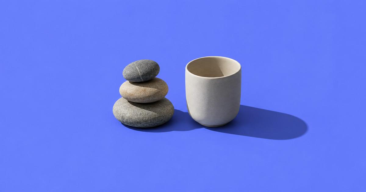 Tres piedras de río apiladas junto a una taza de cerámica mate